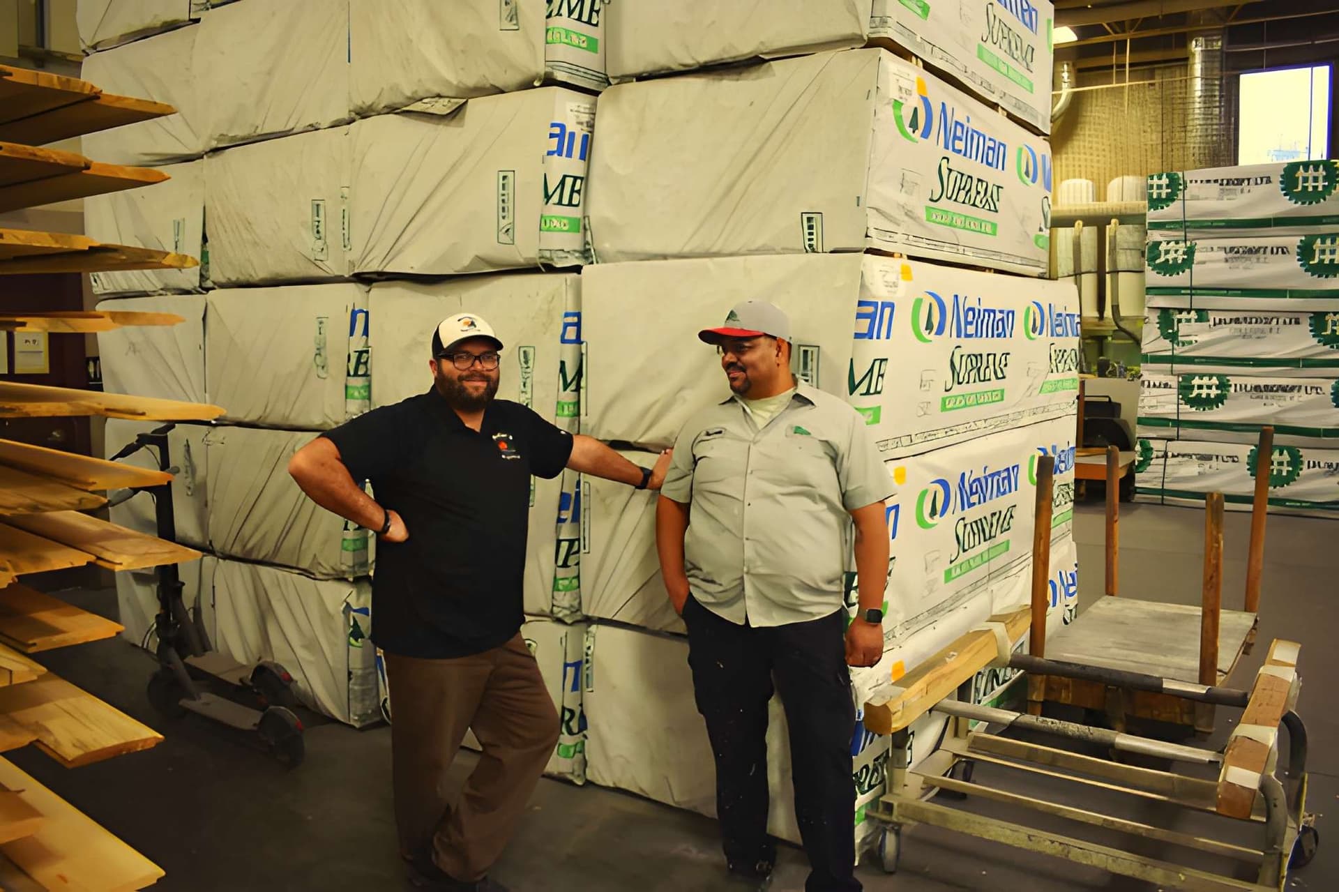 Two Woodco employees posing in front of lumber pallets in the warehouse